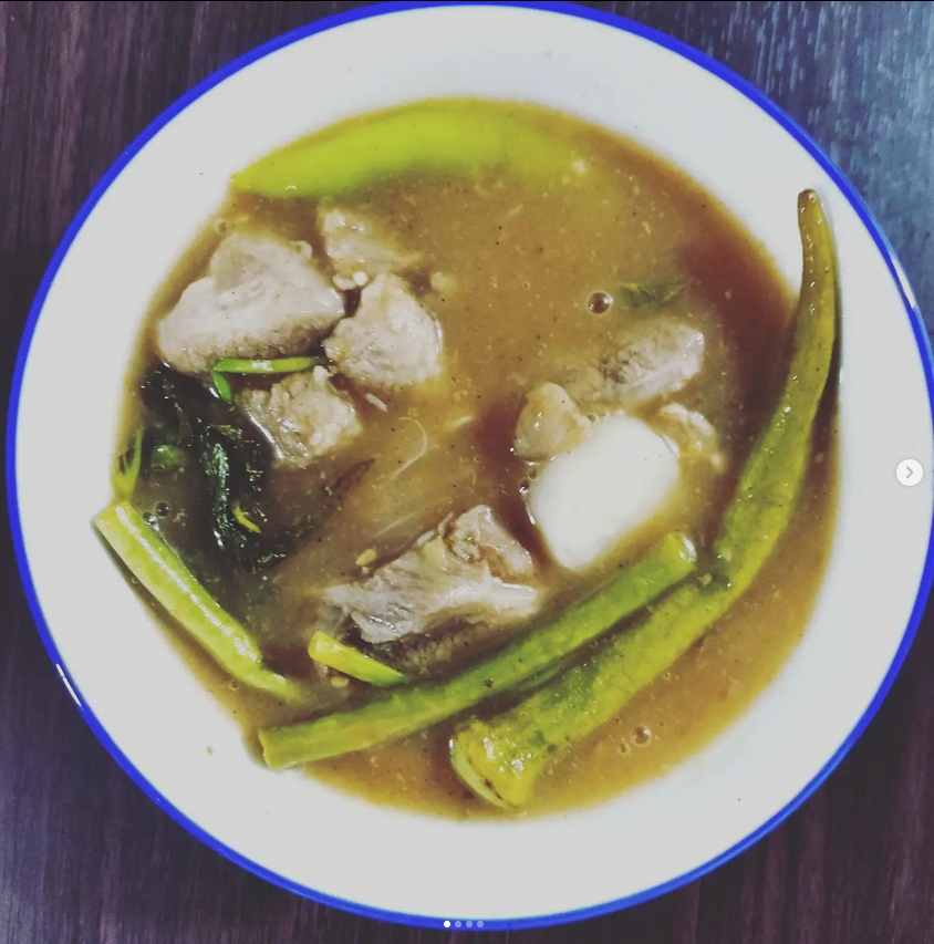 Sinigang in a white bowl with blue edge.